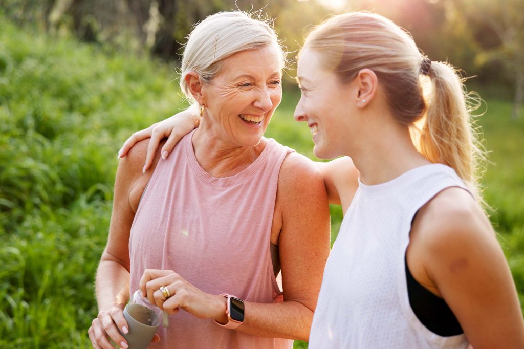 Mature woman, daughter and outdoor on walk for fitness, wellness and exercise in nature with laughing.